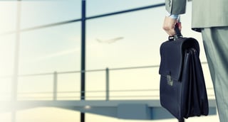 Back view of businessman at airport with suitcase in hand