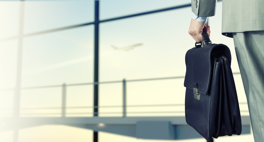 Back view of businessman at airport with suitcase in hand-1